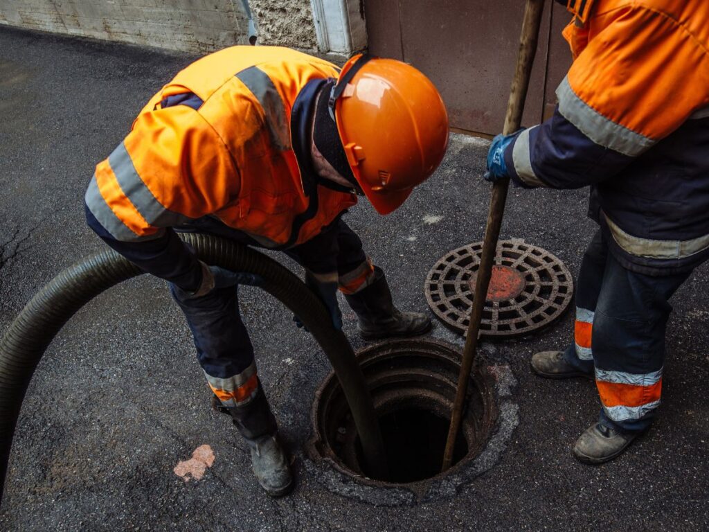 Utility workers perform maintenance on sewer on road